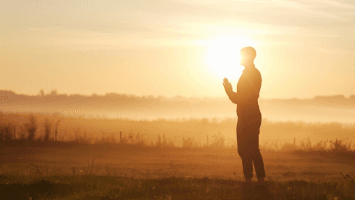A real human person standing at sunrise in quiet prayer, symbolizing seeking guidance and clarity at the beginning of a new season.
