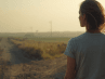 A person standing at a forked road, pausing before choosing a direction.