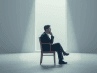 A person sitting thoughtfully in a minimalist room, representing patience and hope while healing broken relationships.